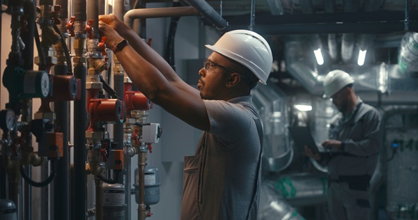 African-American-heavy-industry-worker-inspects-piping-system-1897364731_2388x1259